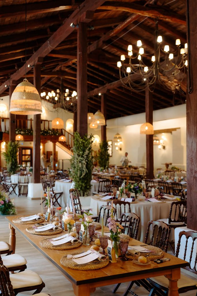 Vista general de la sala de bodas en la Antigua Fábrica de Harinas de Madrid, con techos altos, vigas de madera oscura y una mesa rectangular principal.